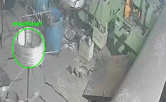 A frame from a steel plant camera, with the monitored region outlined in green around a wire coil on a drawing machine